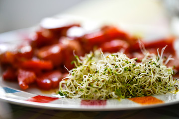 Wall Mural - seeds sprouted in a glass jar in a plate with red tomatoes