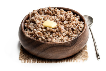 Boiled buckwheat with butter in wooden bowl isolated on white