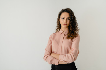 mujer de pelo morena con camisa elegante rosa con los brazos cruzados