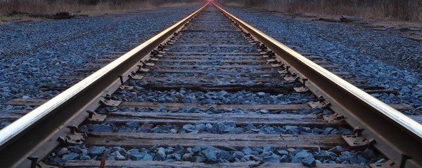 Perspective view of railroad tracks with sunset in the background
