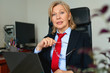 © JENOCHE - Portrait of mature woman in suit and red tie at office.