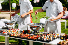 Two Chefs Prepare Food Outdoors For A Party