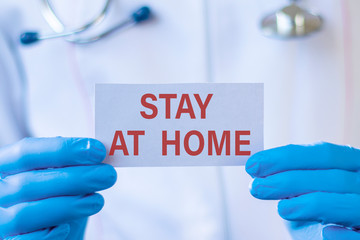 Wall Mural - Stay at home text on card and hands holding it. Healthcare or prevention concept.