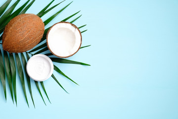 coconut oil cream with tropical palm leaf on blue background. flat lay, top view. spa natural organi