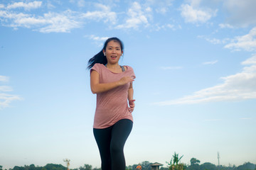 Wall Mural - outdoors jogging workout - young happy and dedicated Asian Chinese woman running at beautiful ccountryside road under a blue sky on enjoying fitness and cardio activity