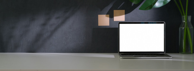 Close up view of trendy workspace with mock-up laptop, plant vase and copy space