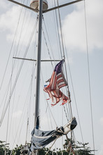 Low Angle View Of Torn American Flag On Boat Against Sky