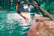 Full Length Of Shirtless Boy Jumping In Water