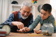 © JustLife - Grandpa and grandson saving money. Grandfather teaching grandchild how to save money.