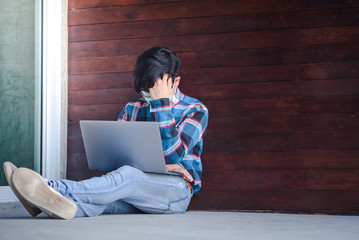 Handsome Asian men working in freelance jobs wear protective masks sitting stressed from unemployment at home with a notebook computer. Unemployment concept fails during Covid-19.