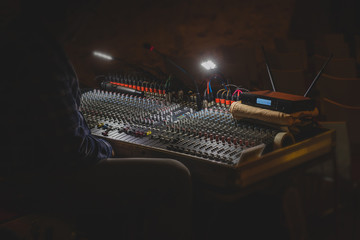 Audio mixing board on an event. Visible remote microphone, receiver, handheld microphone. Noon staged photo of a mixing board at an event.