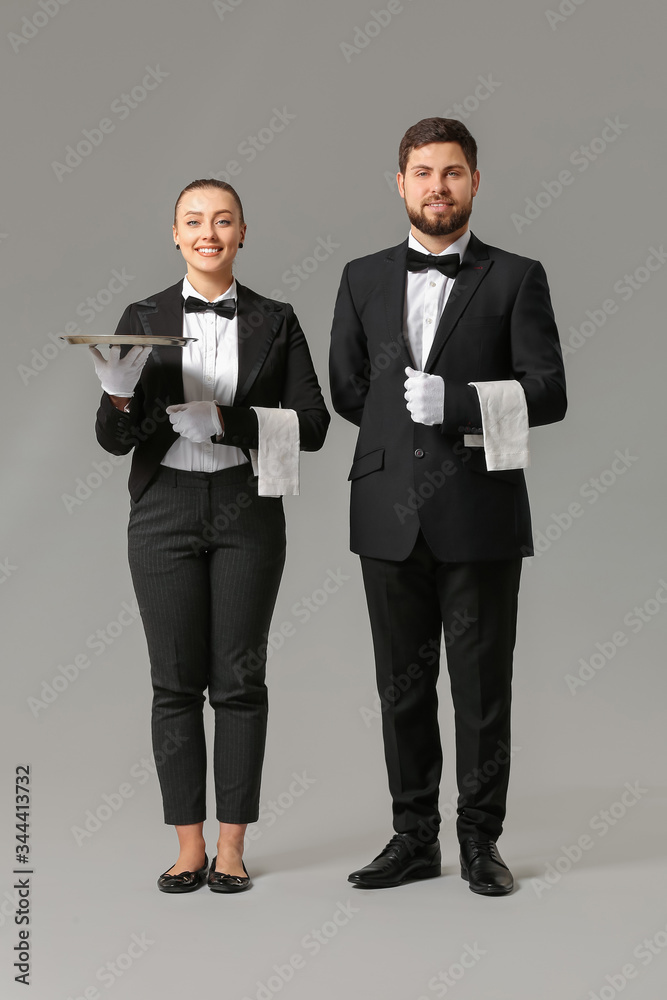 Male and female waiters on grey background