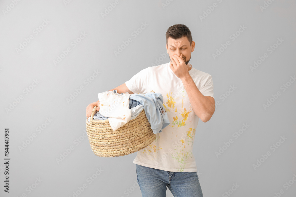 Displeased man with dirty clothes on light background