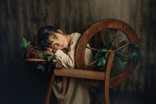 Indoor Portrait Of Young Child Girl With Wool Spinning Wheel On Wooden Background