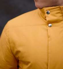 Poster - man stands in yellow winter jacket on grey background