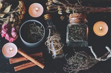 Flat Lay Of Kitchen Witchery Using Herbs And Spices Found At Home. Herbal Magick In Wicca And Witchcraft. Glass Jars Filled With Dried Herbs And Spices, Cinnamon, Flowers, Camomile, Burning Candles
