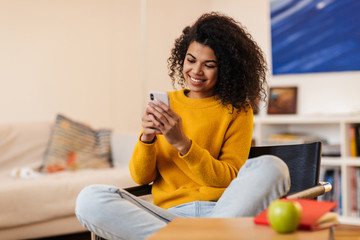 Wall Mural - Image of african american woman using cellphone while sitting on chair