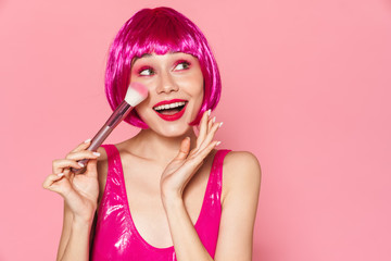 Wall Mural - Image of young happy girl wearing wig smiling and holding powder brush