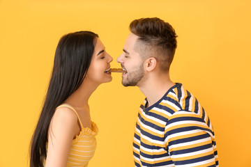 Wall Mural - Beautiful young couple with tasty chocolate on color background