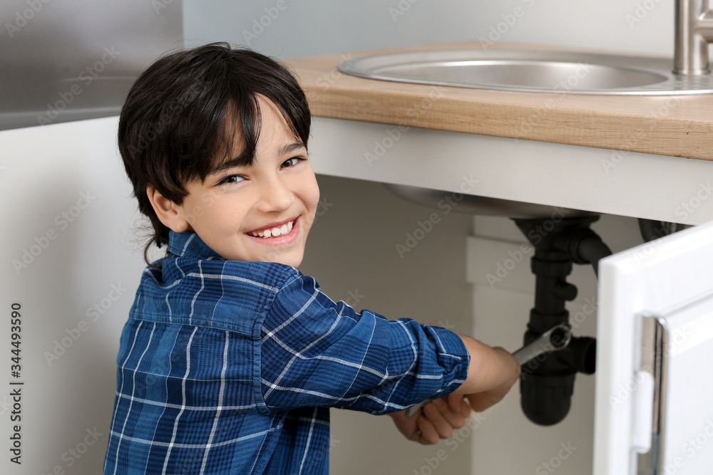 Little plumber repairing sink in kitchen