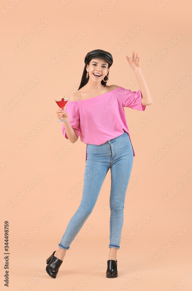Happy young woman with cocktail on color background