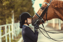 Young Teenage Girl Equestrian Kissing Her Favorite Red Horse. Multicolored Outdoors Horizontal Image. Dressage Outfit 