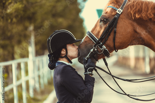 Fotomural Young teenage girl equestrian kissing her favorite red horse
