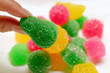 Woman's Fingers Picking a Vibrant Green Sugar Coated Jelly Candies from the Candy Pile
