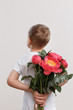 © Natali Illar - A boy in white t-short holds a bouquet of red tulips behind his back. The concept of surprise. Without face.