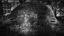 A Monochrome Cemetery Stone With Hands