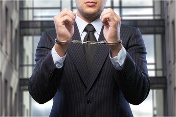 Wall Mural - Young businessman in handcuffs on the background of diffuse court