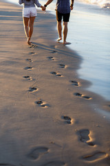 Young couple running on a tropical beach at sunset