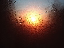 Full Frame Shot Of Wet Glass With Raindrops During Sunset