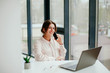 © Kateryna Ivaskevych - young businesswoman working on laptop in the office. portrait of businesswoman. working in the office. happy business woman talking on the phone in the workplace. focused woman working.
