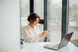 © Катя Іваськевич - young businesswoman working on laptop in the office. portrait of businesswoman. working in the office. happy business woman talking on the phone in the workplace. focused woman working.