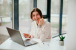 © Катя Іваськевич - young businesswoman working on laptop in the office. portrait of businesswoman. working in the office. happy business woman talking on the phone in the workplace. focused woman working.