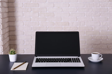 Wall Mural - Creative workspace of a blogger. White laptop computer on wooden table in loft style office with brick walls. Designer's table concept. Close up, copy space, background.