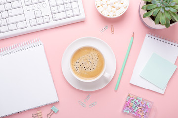 Woman office workplace with cup of coffee and pastel colorful stationery accessories on pink background. Top view