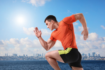 Canvas Print - Athletic young man running near sea on sunny day