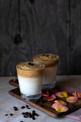 Two glasses of iced Dalgona coffee on a wooden background with copy space.