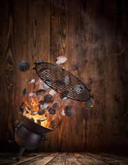 Wall Mural - Kettle grill with hot briquettes and cost iron grate flying in the air. Freeze motion barbecue concept.