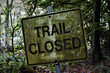 Trail Closed sign on a hiking trail.  Covered in moss and dirt, kind of spooky.