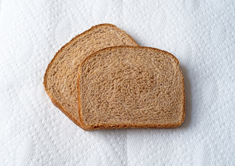 Two slices of wheat bread on paper towels