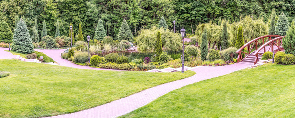 Panorama of the spring park in Mezhigorye near Kiev, Ukraine. Unique landscaping, a beautiful lake and a magnificent decorative garden against the backdrop of deciduous forest.
