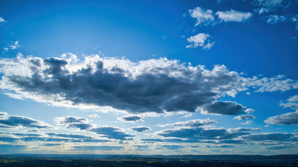 Wall Mural - Blue sky and multiple clouds background showing a horizon and a hidden sun