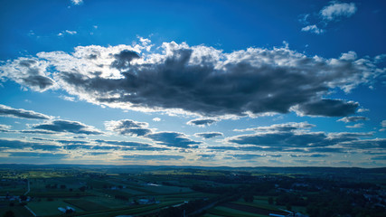 Wall Mural - Blue sky and multiple clouds background showing a horizon and a hidden sun