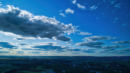 Wall Mural - Blue sky and multiple clouds background showing a horizon and a hidden sun
