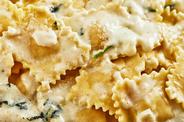 Poster - Tasty cooked ravioli with cream sauce, cherry tomatoes, sunflower oil and basil on a light wooden background.