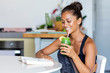 Latin woman staying healthy at home having a green juice