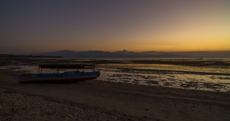 Wall Mural - Wooden traditional boat at the beach on low tide evening sunset scene at Ai Lemak pantai in near Sumbawa Besar town